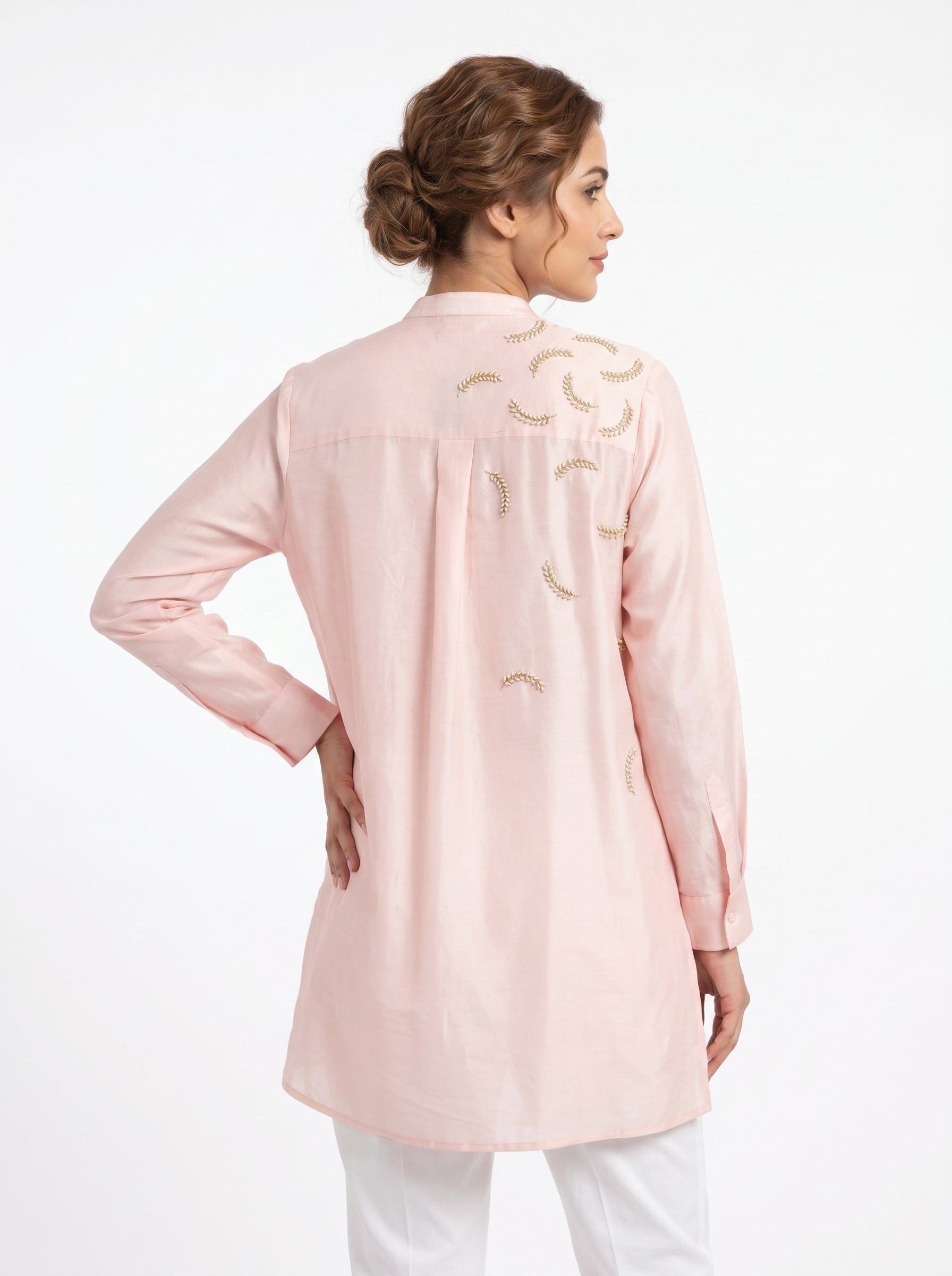 Woman wearing a light pink embroidered jacket on a white background