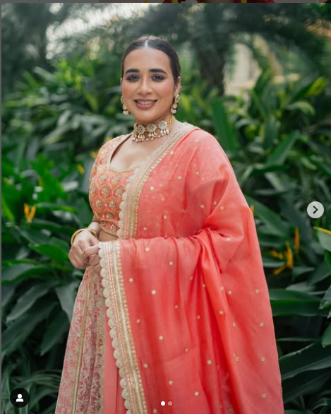 A woman wearing a pink lehenga set with gold and silver foil print and dori embroidery.