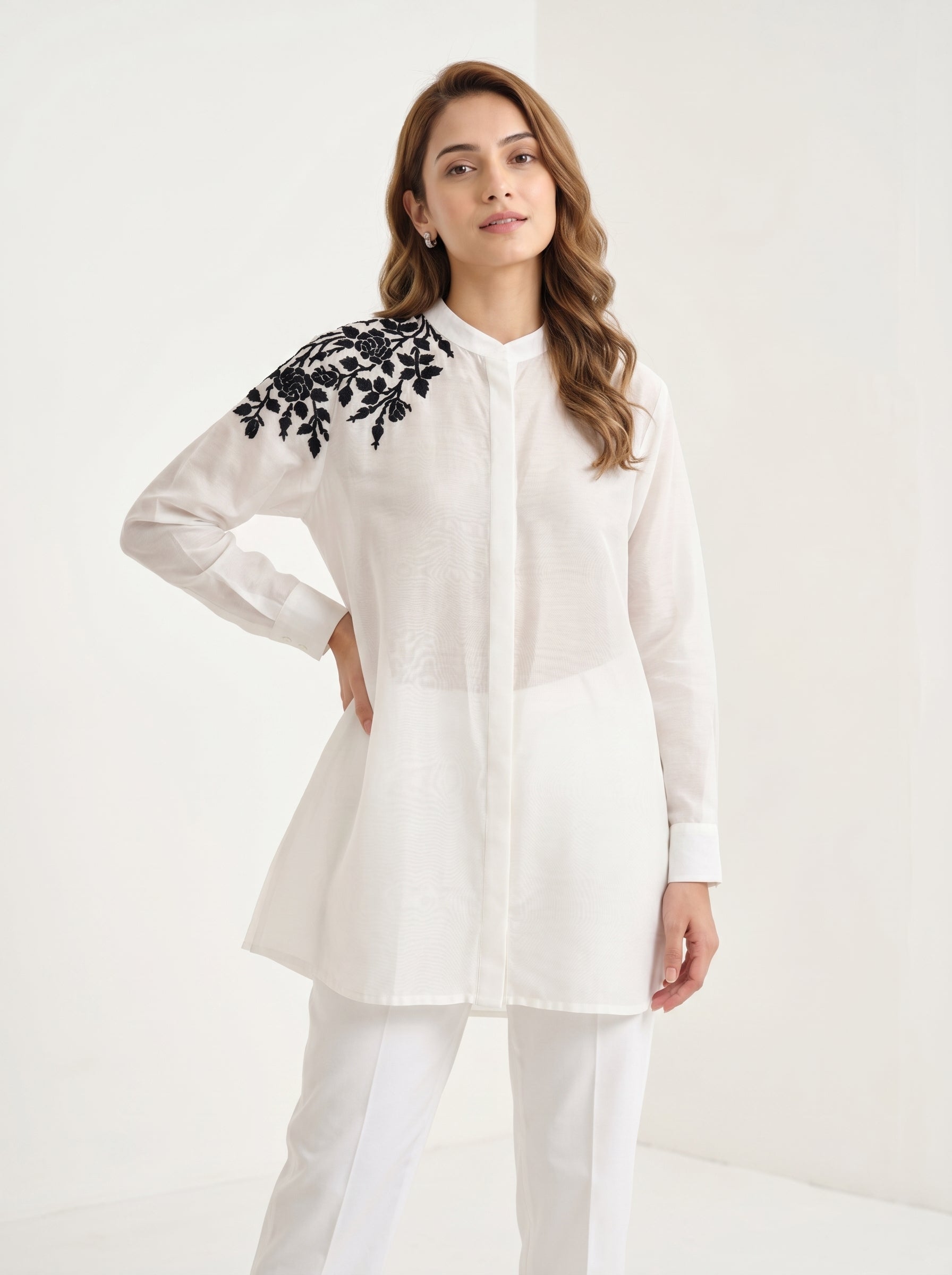 Woman wearing a white kurta with black embroidery on a white background